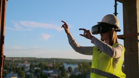 A-woman-engineer-at-a-construction-site-in-virtual-reality-glasses-moves-her-hands-simulating-the-work-of-the-interface-of-the-future-innovative-control-of-the-construction-of-buildings